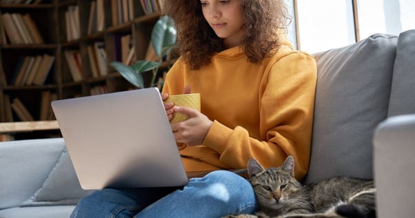 Cat sitting beside woman on the sofa.