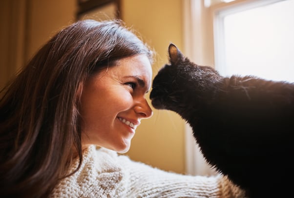 Woman and cat leaning their faces together.