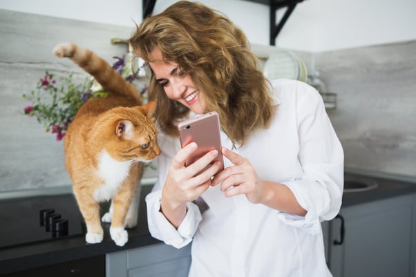 Happy woman showing a cat pictures on her phone.