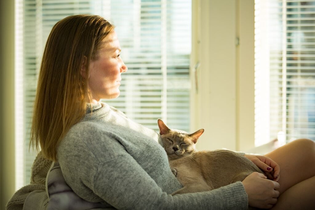 Egy nő ül a székben ölében egy szürke macskával 