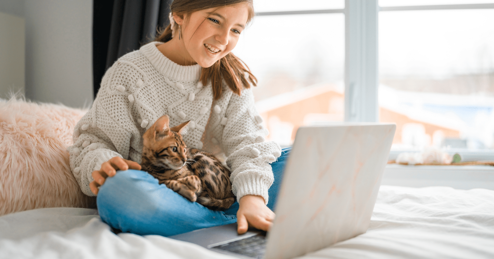young girl using laptop with cat in her lap